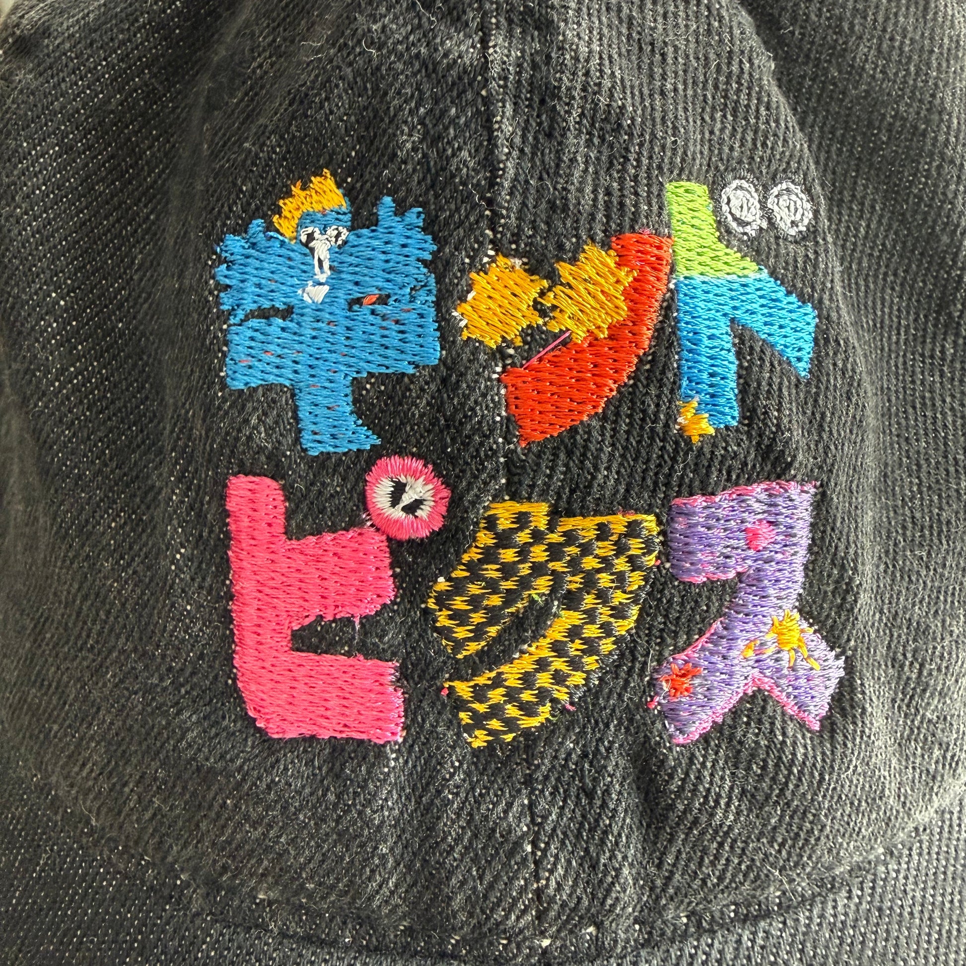 Black cap with colorful embroidered letters on a blurred background