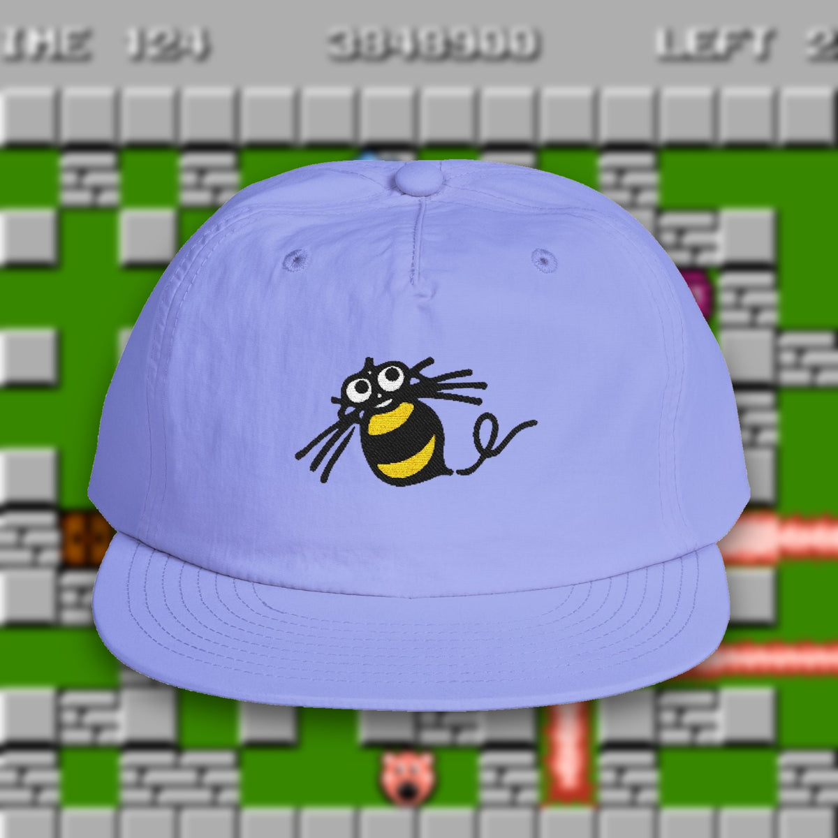 Hudson Soft Bee Surf Cap in lapis blue, embroidered Hudson Soft bee, over a blurred NES Bomberman gameplay screen