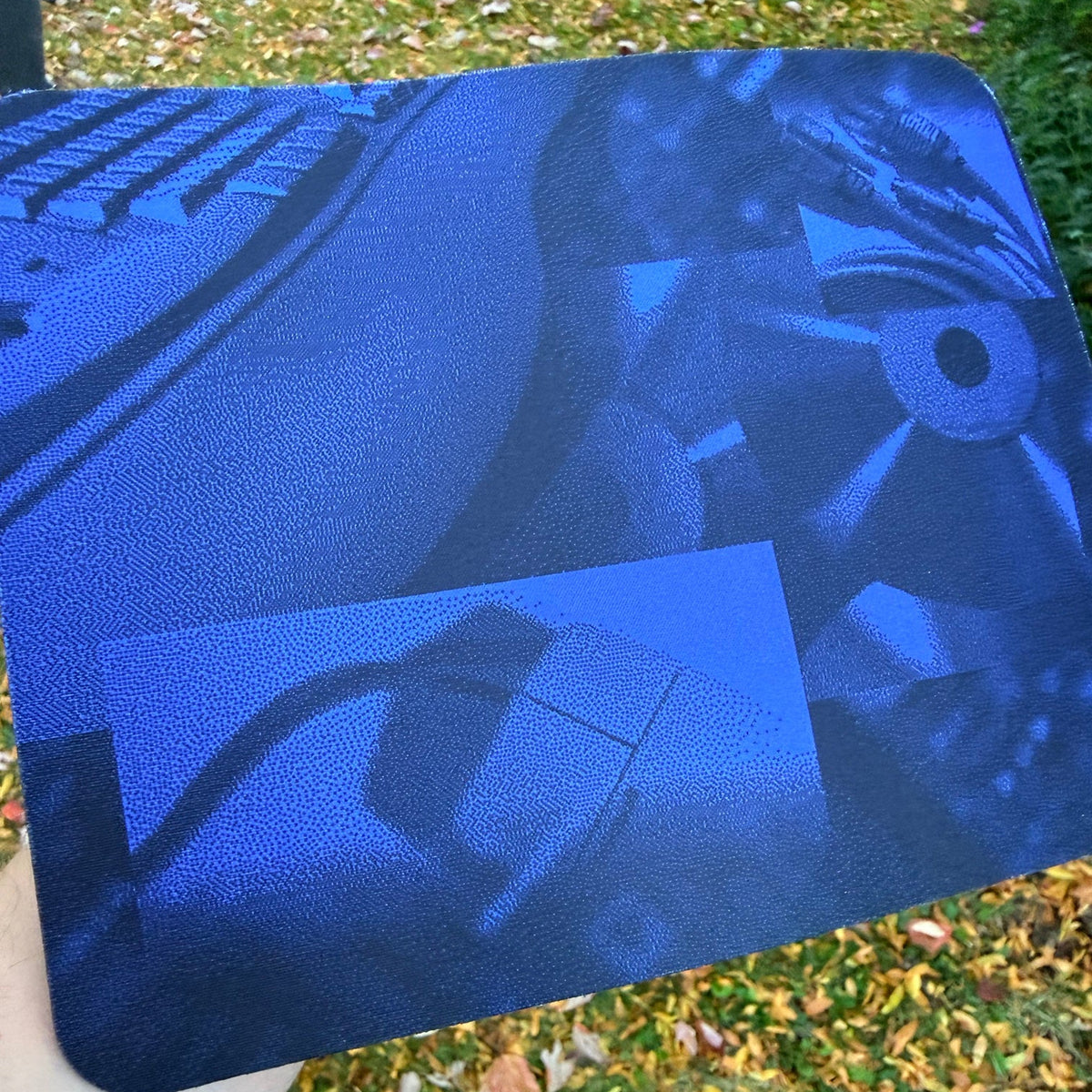Windows 95 Setup Mouse Pad held outdoors, showing the dithered blue collage of a keyboard, mouse and cables